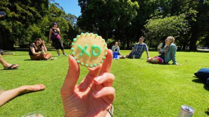 A hand holds up a cookie with XD on it in icing.
