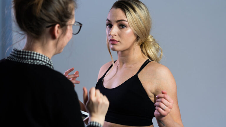 A model stands still as another woman stands in front of the camera, preparing her for the upcoming photoshoot for Ottawa Plastic Surgery.