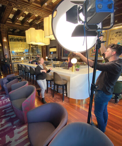 A man adjusts the light in a bar while a woman helps direct.