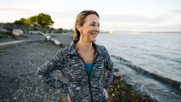 A woman smiles as she looks out at the ocean.