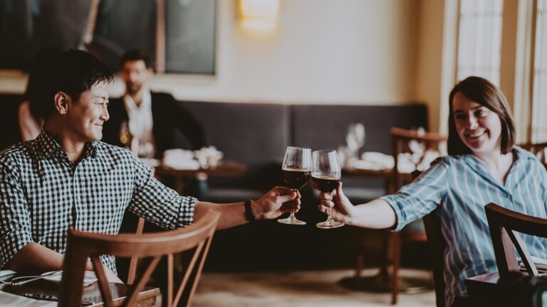 Two people clink glasses in one of the Vintage Hotels restaurants.