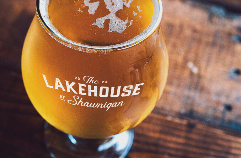 A photo of a glass of beer. The glass is branded with The Lakehouse at Shawnigan.
