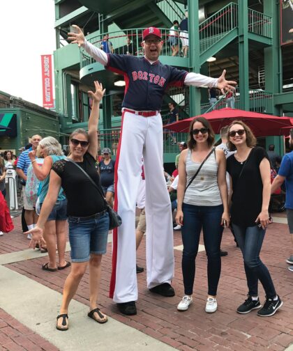 A man on stilts and three women pose for a photo.