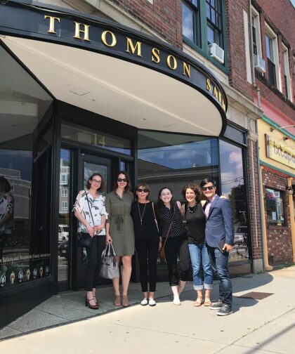 Six people stand smiling in front of the Thomson Safaris office.