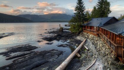 Cabins look out onto a rugged coastline with mountains in the distance.