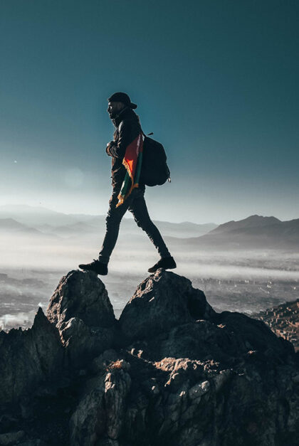 A man walks over the rocks of a mountain peak.