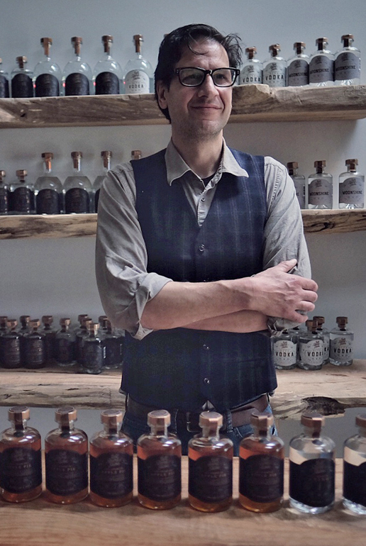 A man stands in front of glass bottles.